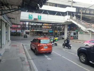 a small car driving down a city street with motorcycles at BEN HOUSE in Bangkok