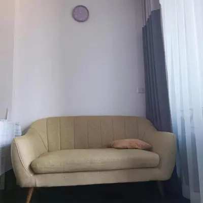 a couch in a room with a clock on the wall at Sathon Luxury High-rise Apartment City View KingPower ,IconSiam ,BNH,Silom in Bangkok