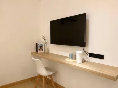 a flat screen tv on a wall with a white chair at Ascella Bangkok Hotel in Makkasan