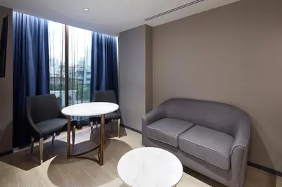 a waiting room with a couch and a table and chairs at Grace At Five by Grace Hotel Bangkok in Bangkok