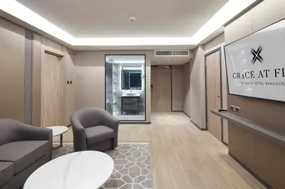 a lobby with a waiting room with chairs and a tv at Grace At Five by Grace Hotel Bangkok in Bangkok