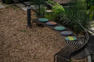 a black bench with colorful seats in a garden at neil niwas in Bangkok