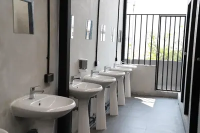 a row of white sinks and mirrors in a bathroom at The Cube Hostel Khaosan in Bangkok
