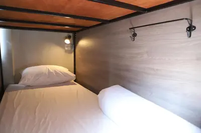 a bedroom with a white bed and a wooden wall at The Cube Hostel Khaosan in Bangkok