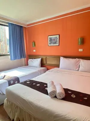 two beds in a hotel room with orange walls at Asia Inn Bangkok 2022 in Bangkok