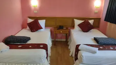 a room with two beds and a table with a telephone at Asia Inn Bangkok 2022 in Bangkok