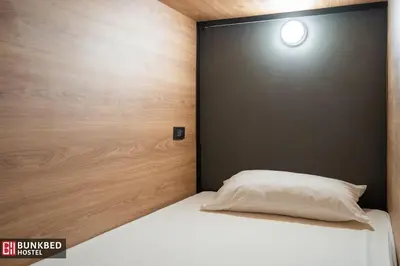 a bed with a white pillow in a room at Bunkbed Hostel in Makkasan