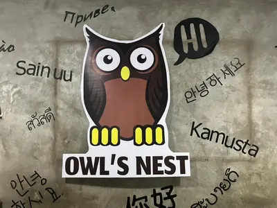 an owl is sitting on a sign with writing at Owl's Nest suk 30 in Bangkok