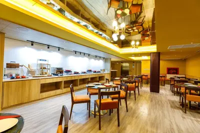 a restaurant with tables and chairs and a counter at Benjarong Hotel Bangkok Ratchada in Bangkok