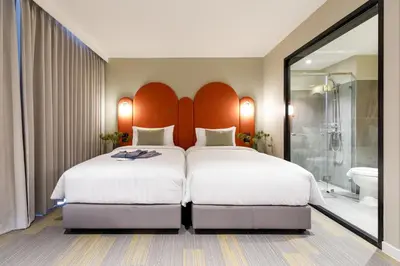 a hotel room with two beds and a shower at Benjarong Hotel Bangkok Ratchada in Bangkok