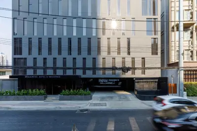 a car driving down a street in front of a building at Benjarong Hotel Bangkok Ratchada in Bangkok
