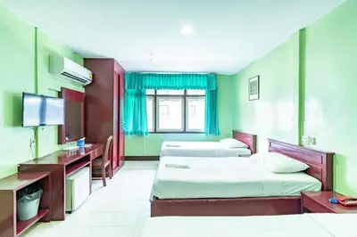 a hotel room with two beds and a television at Woodlands Inn in Bangkok