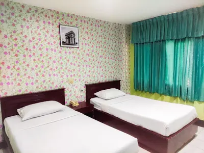 two beds in a room with green curtains at Woodlands Inn in Bangkok