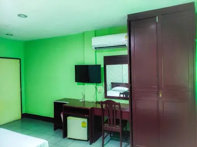 a bedroom with a desk and a mirror and green walls at Woodlands Inn in Bangkok