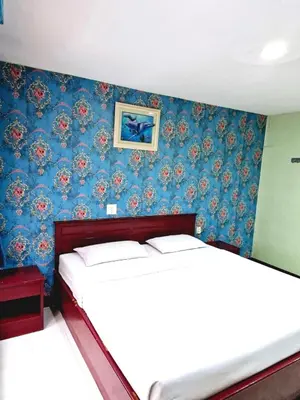 two beds in a bedroom with blue wallpaper at Woodlands Inn in Bangkok