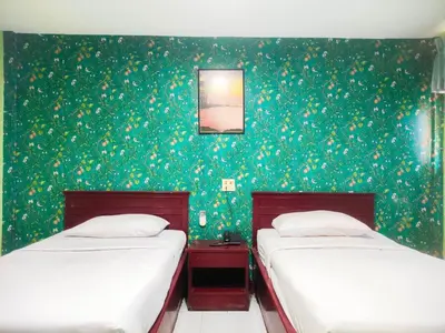 two beds in a room with green wallpaper at Woodlands Inn in Bangkok