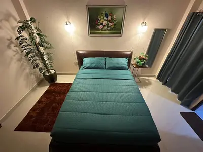 a green bed in a room with a plant at 66 Apartment in Ban Khlong Nong Yai