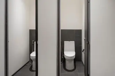 a bathroom with a toilet and two sinks in it at Lilit Bang Lumphu Hotel in Bangkok