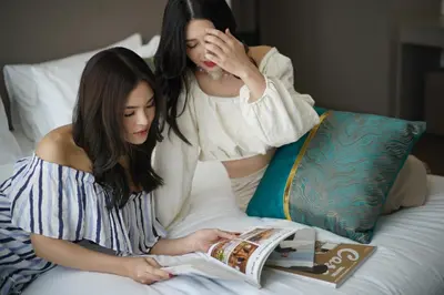 two women laying on a bed reading a book at The Rich Residence Sukhumvit Nana in Bangkok