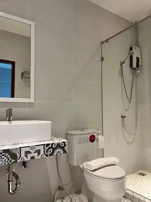 a bathroom with a shower and a toilet and a sink at Aowmana Hotel in Makkasan