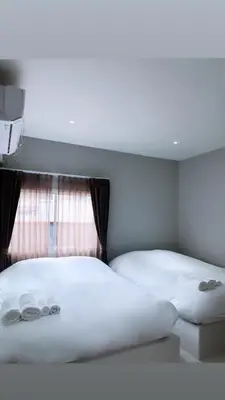 a bedroom with two beds with white sheets and a window at Aowmana Hotel in Makkasan