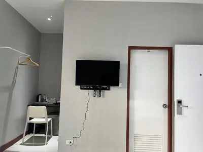 a room with a television on a wall with a chair at Aowmana Hotel in Makkasan