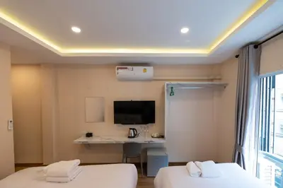 a hotel room with two beds and a desk at Amber Inn in Bangkok