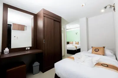a hotel room with two beds and a mirror at Royal Asia Hotel Pratunam in Bangkok