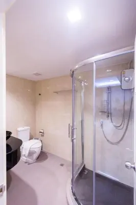a bathroom with a toilet and a glass shower at Royal Asia Hotel Pratunam in Bangkok