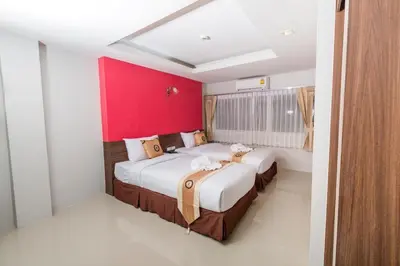 a bedroom with two beds and a red wall at Royal Asia Hotel Pratunam in Bangkok