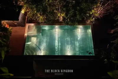 a swimming pool at night with a sign that reads the hidden kingdom at The Black Kingdom - เดอะ แบล็ค คิงดอม in Bangkok