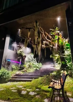 a bench sitting in the grass next to some stairs at The Black Kingdom - เดอะ แบล็ค คิงดอม in Bangkok