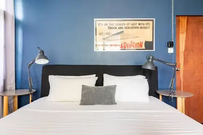 a bed with two lamps and a blue wall at Bang Chak Homestay in Amphoe Phra Khanong