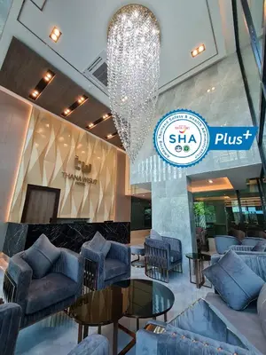a lobby with couches and tables and a chandelier at Thana Wisut Hotel in Bangkok