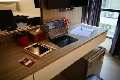 a laptop computer sitting on a desk in a room at Thana Wisut Hotel in Bangkok