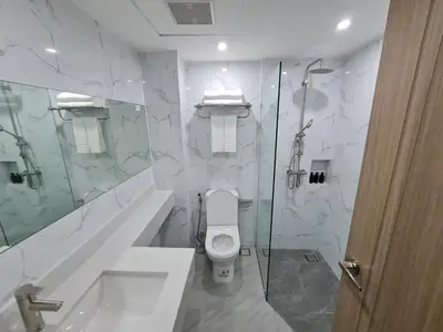 a white bathroom with a toilet and a shower at Thana Wisut Hotel in Bangkok