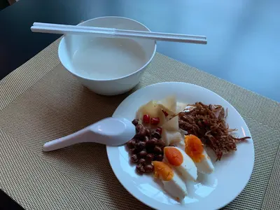 a plate of food with a spoon and a bowl of milk at Thana Wisut Hotel in Bangkok