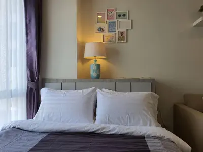 a bedroom with a bed with white pillows and a lamp at I'M Chinatown Residence Yaowaraj Bangkok Watmungkorn MRT Station in Bangkok