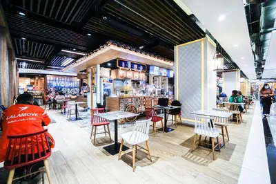 a restaurant with tables and chairs and people in the background at I'm Chinatown Residence in Bangkok