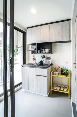 a kitchen with wooden cabinets and a yellow shelf at I'm Chinatown Residence in Bangkok