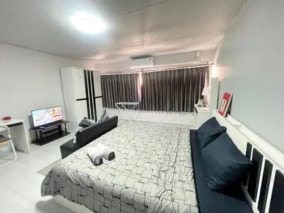 a room with a bed and a couch and a television at Lively Impact C3-C9 in Nonthaburi