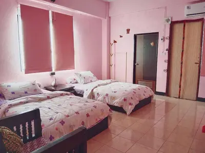 two beds in a room with pink walls at Worakarn Apartment 1 in Bangkok