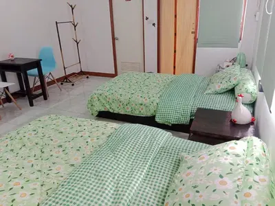 a bedroom with two beds with green sheets and a table at Worakarn Apartment 1 in Bangkok