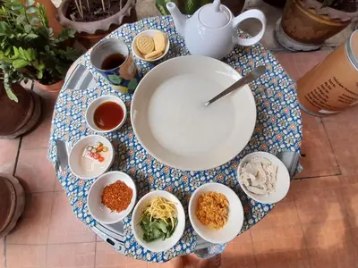 a table with a plate and bowls of food on it at Worakarn Apartment 2 in Bangkok