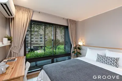 a bedroom with a bed and a desk and a window at GROOVE AT SIAM in Pom Prap