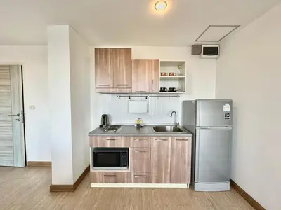 a kitchen with wooden cabinets and a stainless steel refrigerator at Town Sukhumvit 71 in Bangkok