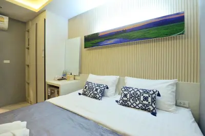 a bedroom with a bed with blue and white pillows at De Lux Bangkok Hotel in Ban Khlong Lat Bua Khao