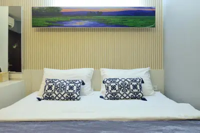 a bed with two pillows and a painting on the wall at De Lux Bangkok Hotel in Ban Khlong Lat Bua Khao