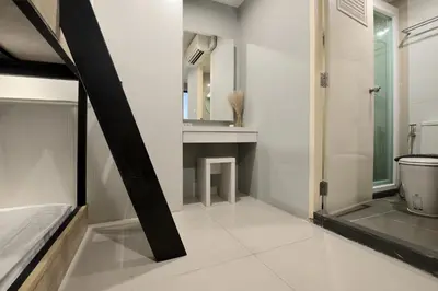 a bathroom with a bed and a sink and a mirror at De Lux Bangkok Hotel in Ban Khlong Lat Bua Khao
