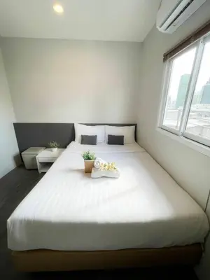 a bedroom with a large white bed with flowers on it at De Lux Bangkok Hotel in Ban Khlong Lat Bua Khao